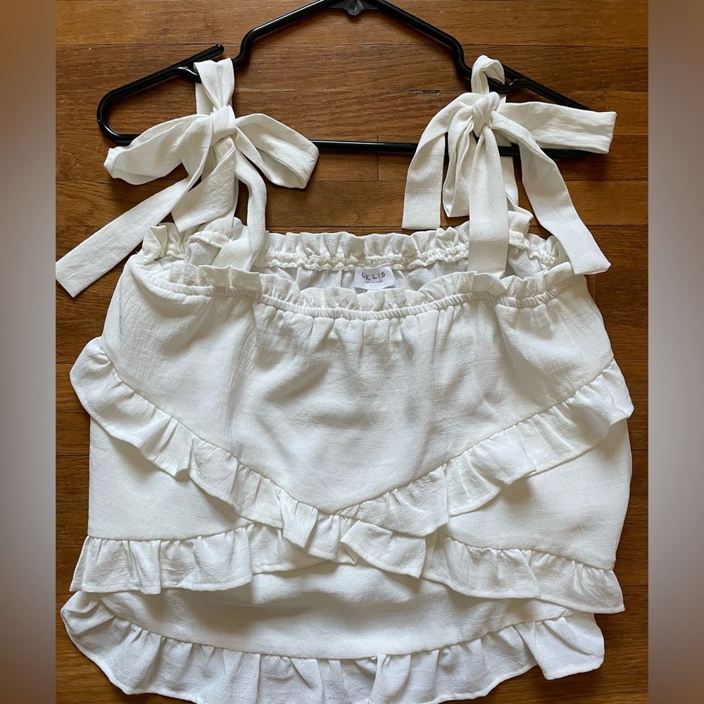 Brand New Without Tags. Lelis. Size Large. White ruffle blouse with ties.